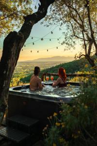 a man and woman sitting in a hot tub with wine glasses at Aura Toscana Boutique in Monsummano Terme