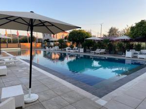 a swimming pool with an umbrella and chairs and tables at Union Villa in Shkodër +23 photos