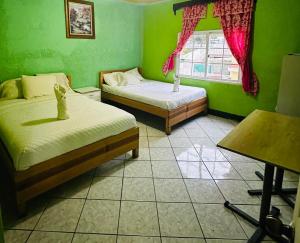 a green room with two beds and a window at Apartamento el Amigo in Panajachel