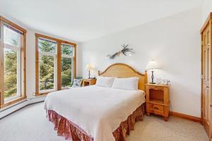 a bedroom with a large bed and two windows at Jay Peak Townhouse in Jay
