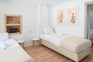 two beds in a bedroom with white walls and wooden floors at Aqua Vero Seaside Residence in Hersonissos