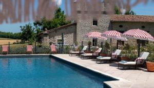 a swimming pool with chairs and umbrellas next to a building at Luxury Gites de Chateau Mirabel - Latour - with saltwater swimming pool and AC in Puylaurens