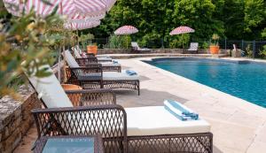 a pool with chairs and umbrellas next to a swimming pool at Luxury Gites de Chateau Mirabel - Latour - with saltwater swimming pool and AC in Puylaurens