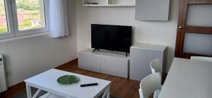 a living room with a tv and a white table and chairs at Barrañán Arena in Arteixo