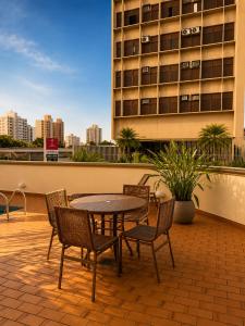 eine Terrasse mit Tisch und Stühlen und ein Gebäude in der Unterkunft Hotel Riviera in Sao Jose do Rio Preto