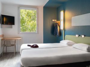 a hotel room with two beds and a window at ibis Budget Paris La Villette 19ème in Paris