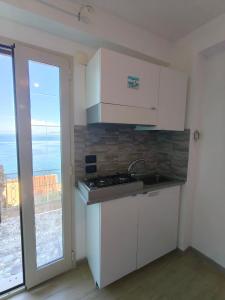 a kitchen with white cabinets and a sink and a window at Scilla Chianalea Suite Mare1 in Scilla