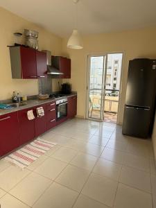 a kitchen with red cabinets and a black refrigerator at Superbe Appartement Bord de mer in Bouznika