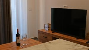a television with a bottle of wine and two glasses at Lazari S Apartments in Himare