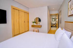 a bedroom with a large white bed and a wooden door at City & Stadium Luxe - Tangier in Tangier