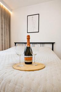 a bottle of wine and two glasses on a bed at Bytom Apartament 24H in Bytom +2 photos