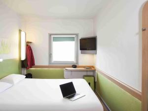 a room with a bed with a laptop on it at ibis budget Lyon Est Chaponnay in Chaponnay