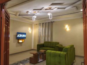 a living room with two green chairs and a tv at Maisonnette KF Golf-Self Catering Apartments in Lubumbashi