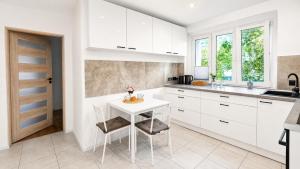 a kitchen with white cabinets and a white table and chairs at Bytom Apartament 24H in Bytom