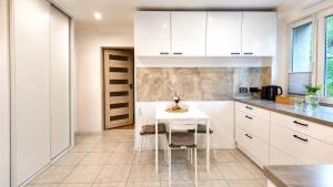 a kitchen with white cabinets and a white table and chairs at Bytom Apartament 24H in Bytom