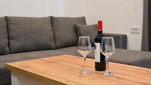 a bottle of wine and two glasses on a table at Lazari S Apartments in Himare