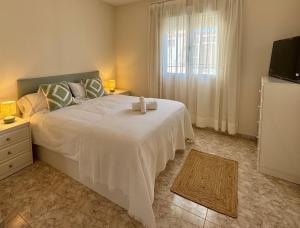 a bedroom with a large white bed with a window at La terraza del Campanario in Ríolobos
