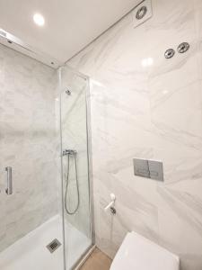 a white bathroom with a shower and a toilet at Casa do Leme in Nazaré
