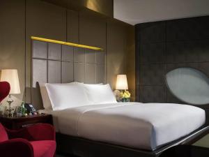 a bedroom with a large white bed and a mirror at Sofitel Kunming in Kunming