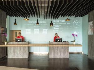 two people sitting at the reception desks in a lobby at Ibis Makassar City Center in Makassar