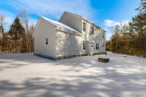 a white building in the snow next to trees at Vermont Ski House in Vermont Ventures