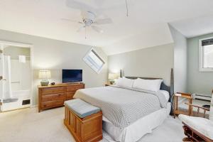 a white bedroom with a bed and a tv at Newton Village 2B in Quechee +49 photos