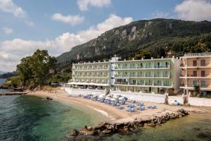 a hotel on a beach with chairs and the water at Corfu Maris in Benitses