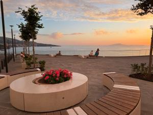 a group of people sitting on benches near the water at Lauro Apartment in Meta