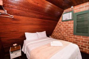 a bed in a room with a brick wall at Chalé com Jacuzzi e Vista Mar - PLH007 in Palhoça +83 photos