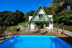 a house with a swimming pool in front of a house at Chalé com Jacuzzi e Vista Mar - PLH007 in Palhoça