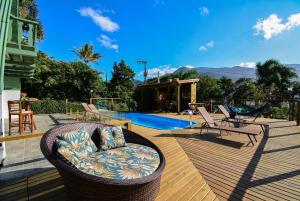 a deck with a wicker couch and chairs next to a pool at Chalé com Jacuzzi e Vista Mar - PLH007 in Palhoça