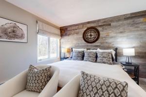 a bedroom with a white bed and a wooden wall at Styles Brook Retreat in Stratton