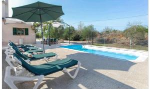 a group of lounge chairs and an umbrella next to a swimming pool at Sa Torreta in Algaida