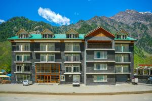 a large apartment building with mountains in the background at Milson Hotel in Naran