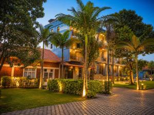 a hotel with palm trees in front of a building at La Planete Hotel in Rubavu