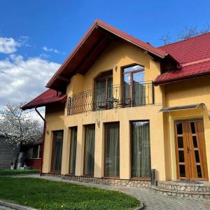 a house with a red roof and a balcony at Pensiunea Vila Mocanilor in Săcele