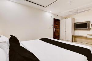 a bedroom with a white bed and a television at Townhouse OAK The Hotel Square Villa in Ghaziabad