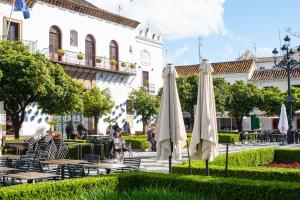 two white umbrellas sitting in a park in front of a building at Luz House Marbella Hostal in Marbella
