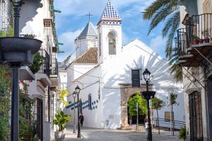 a white church with a steeple on a street at Luz House Marbella Hostal in Marbella +48 photos