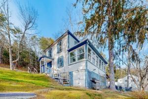 a blue house on a hill with a tree at Lakefront Living in Bomoseen