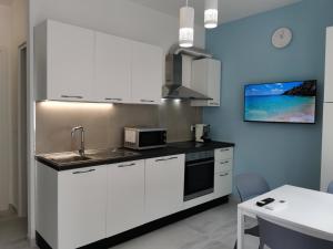 a kitchen with white cabinets and a sink and a microwave at Mare e Trabocchi in Fossacesia