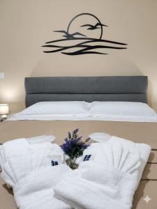 a bed with white towels and a vase of flowers at ANAMI' Suite Apartament in Bovalino Marina