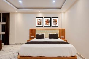 a bedroom with a large bed and two paintings on the wall at Hotel O Kamala Resort in Bhubaneshwar