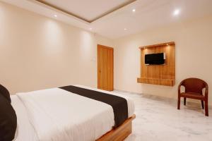 a bedroom with a bed and a tv and a chair at Hotel O Kamala Resort in Bhubaneshwar