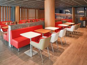 a restaurant with red booths and white tables and chairs at ibis Jundiai Shopping in Jundiaí