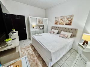 a white bedroom with a large bed and a bathroom at Hospedagem Domiciliar em Lucas do Rio Verde in Lucas do Rio Verde
