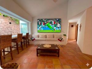 a living room with a couch and a tv on the wall at Casa Golondrina in Xochitepec
