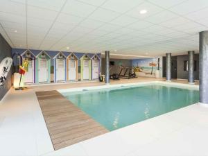 a large swimming pool in a building with a gym at ibis Styles Vierzon in Vierzon