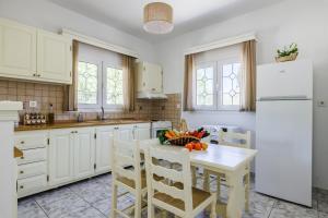 a kitchen with a table and a white refrigerator at Casa Mia Skopelos - Spacious 3-Bedroom House near Stafylos Beach in Skopelos Town