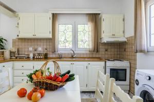 a kitchen with a basket of vegetables on a table at Casa Mia Skopelos - Spacious 3-Bedroom House near Stafylos Beach in Skopelos Town
